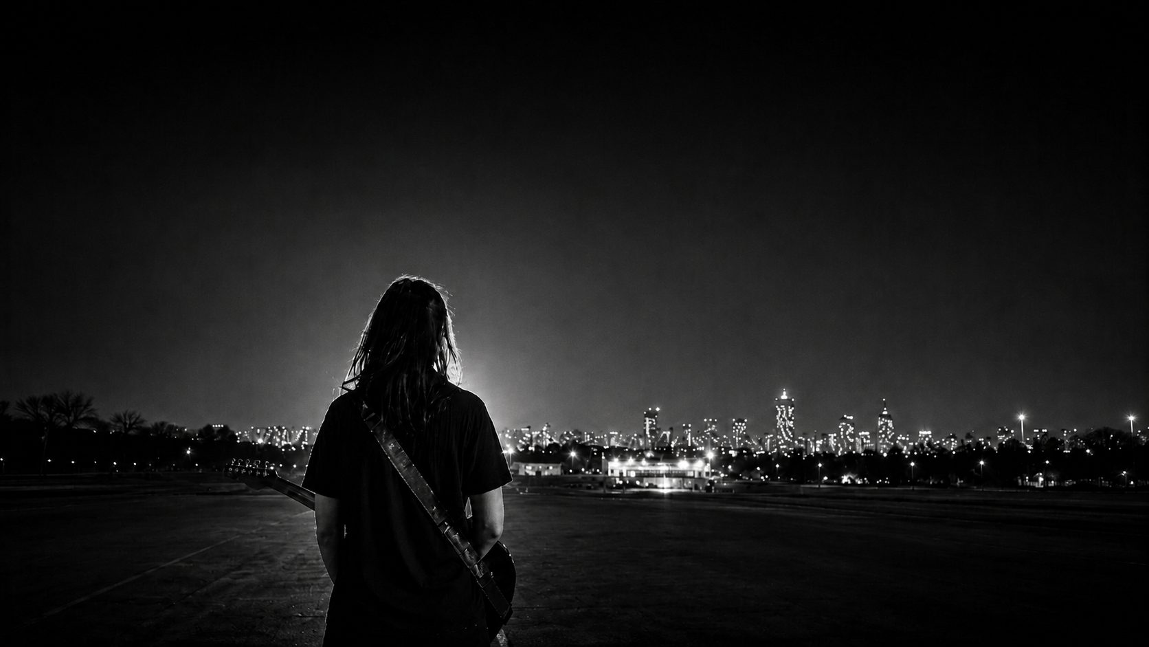 Jenny, seen from behind with a guitar on her back, facing a city skyline at night