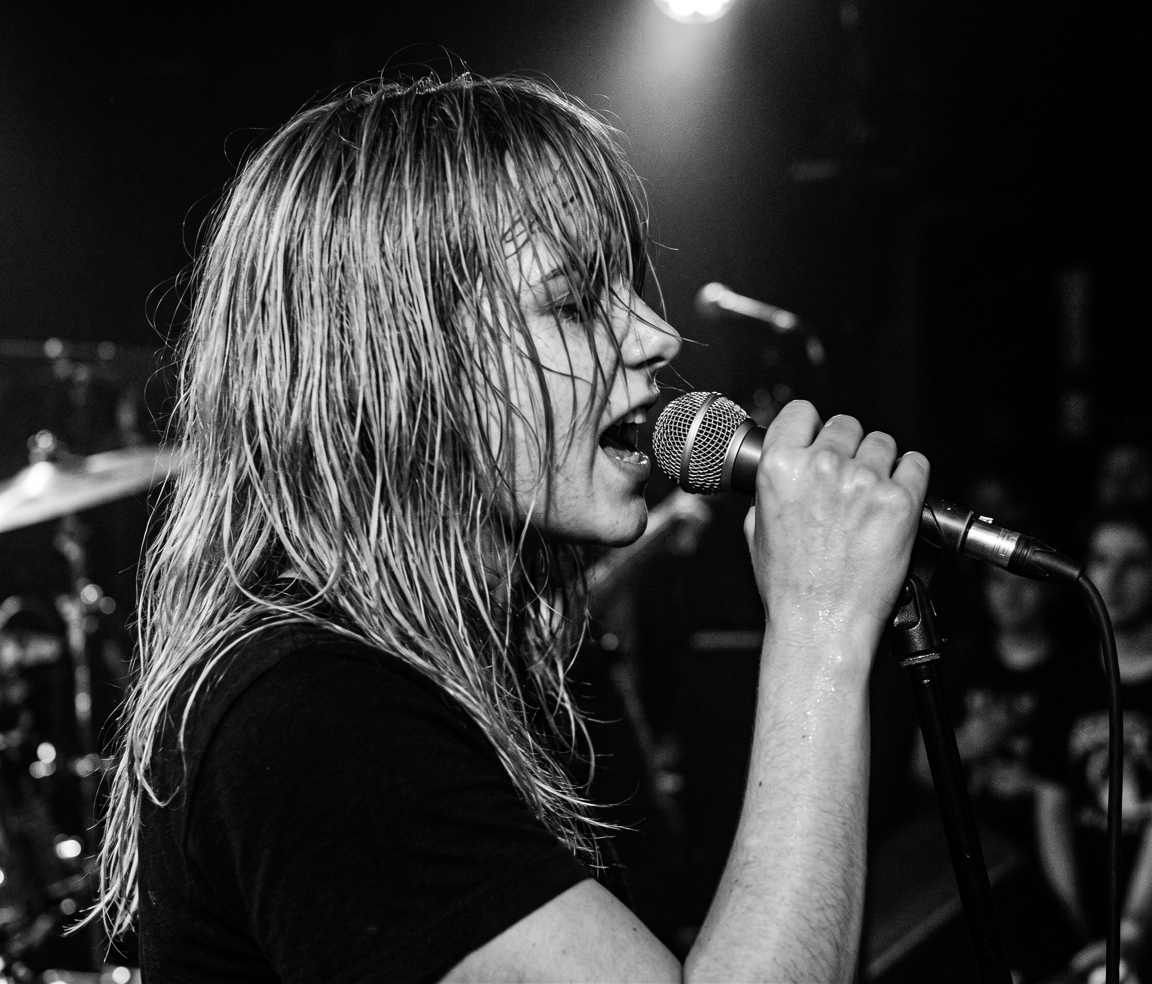 Close-up of a singer gripping a microphone, wet hair covering her face